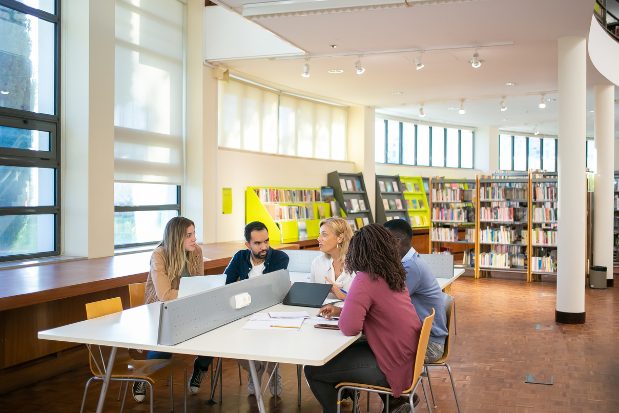 Multiethnic students doing research together in library